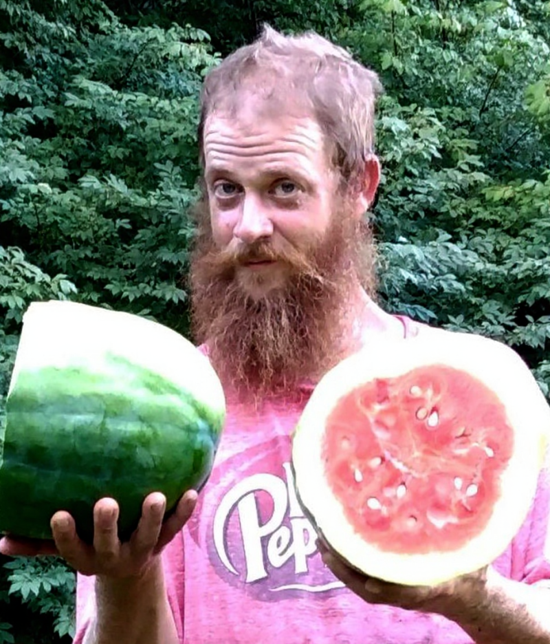 A portrait photo of landscape technician Orphee Ross holding one of the watermelons he grew at Blandy Experimental Farm.