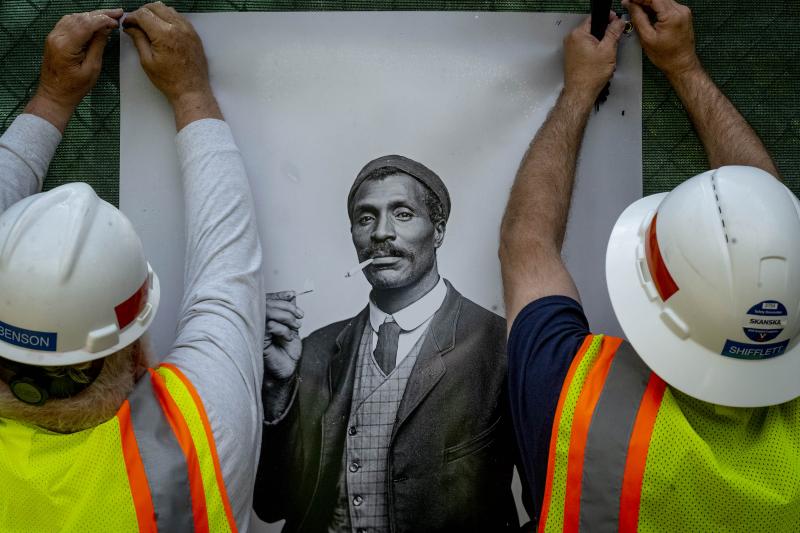 Two Facilities Management employees affix a portrait of Bill Hurley, taken in 1909. Hurley was the coachman for Mayor J. Samuel McCue. (McCue, incidentally, has the dubious distinction of being the last man hung in Charlottesville, executed for shooting h