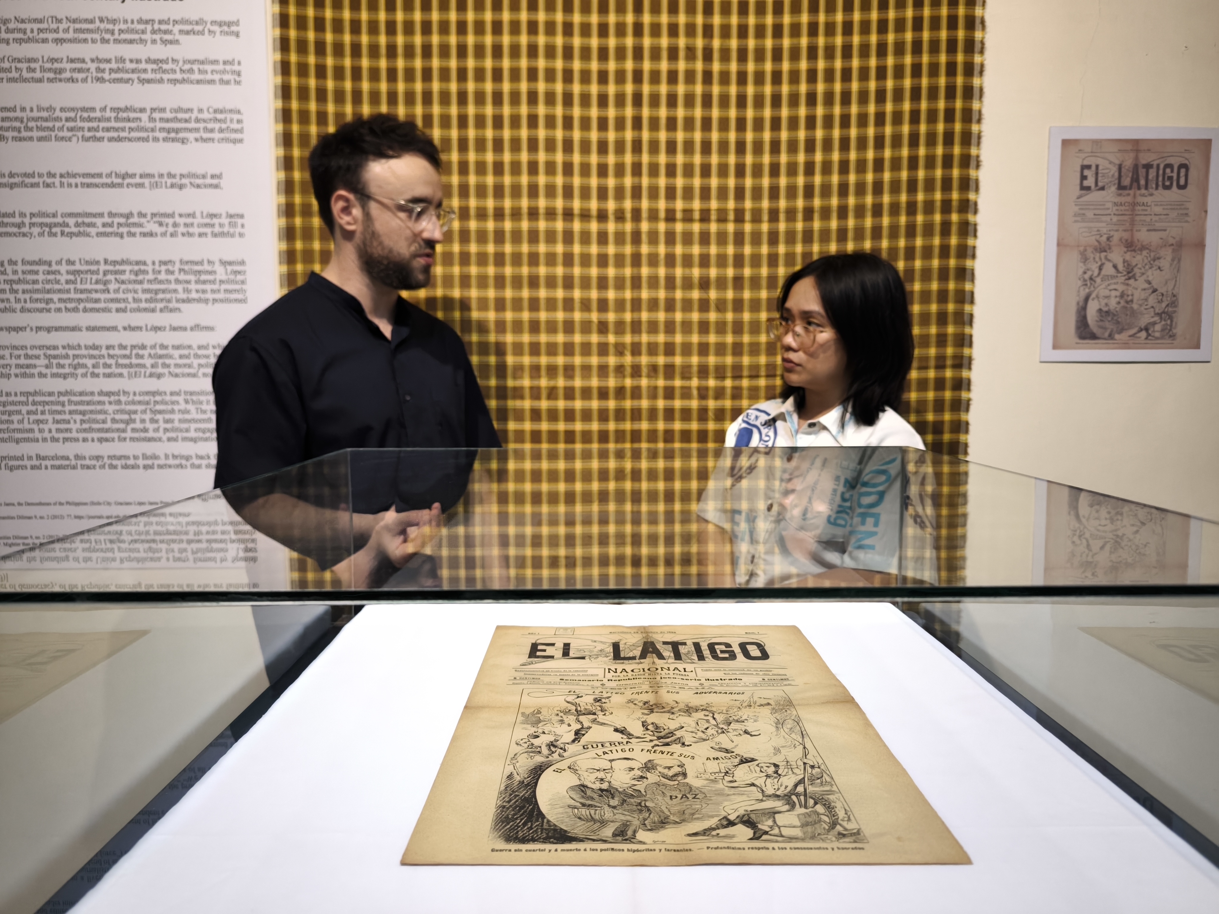 Robert Sanchis-Álvarez and Anthea Redison stand before display case with 19th-century newspaper.