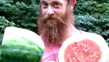 A portrait photo of landscape technician Orphee Ross holding one of the watermelons he grew at Blandy Experimental Farm.