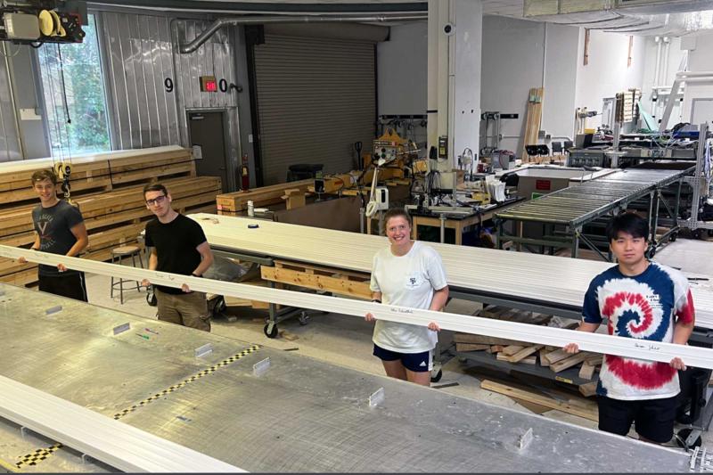 Four undergraduate students who aided production last summer hold up the final “di-counter” that was fabricated, which they all signed. (UVA Experimental High Energy Physics photo)