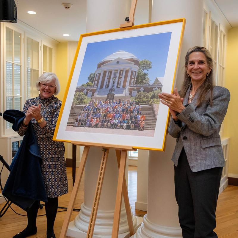 Two alumnae from the Class of '74 flank an unveiled portrait of the first class of undergraduate women to graduate from UVA.