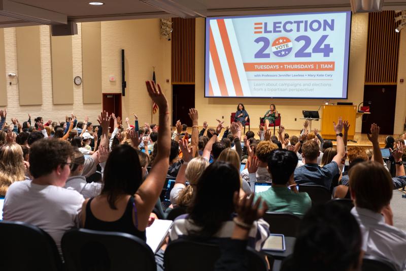 Students in the "Election 2024" Politics class raise their hands in response to a question posed by professors Jennifer Lawless and Mary Kate Cary.