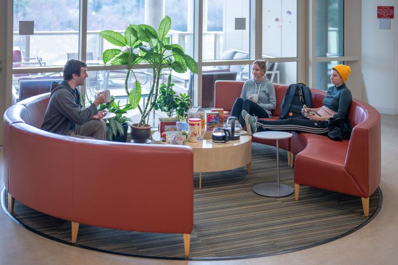 Three Ph.D. students from the Department of Biology are seated in a lounge enjoying a graduate student coffee hour event.