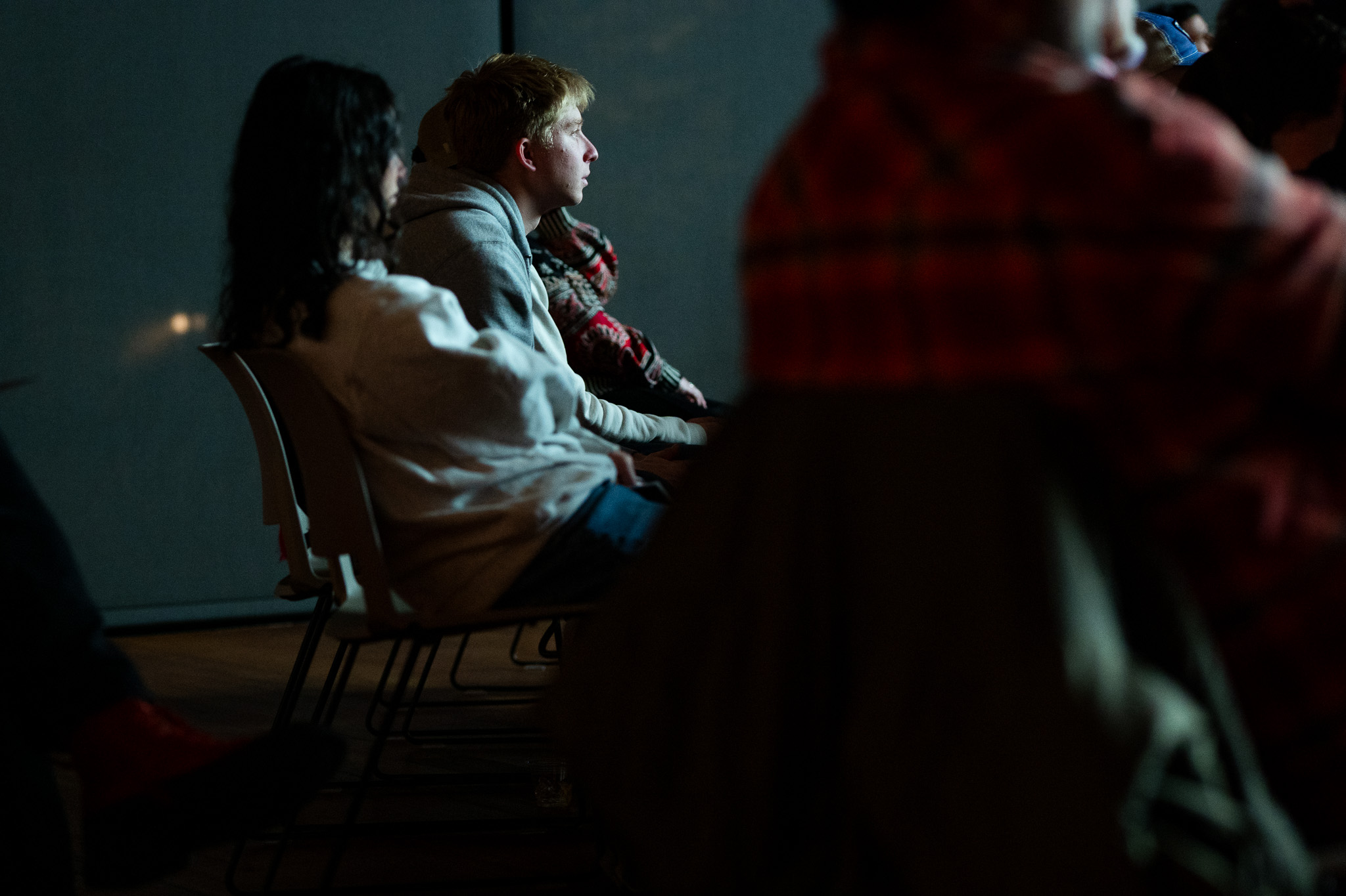 A young man leans forward in his seat as he watches a short film.