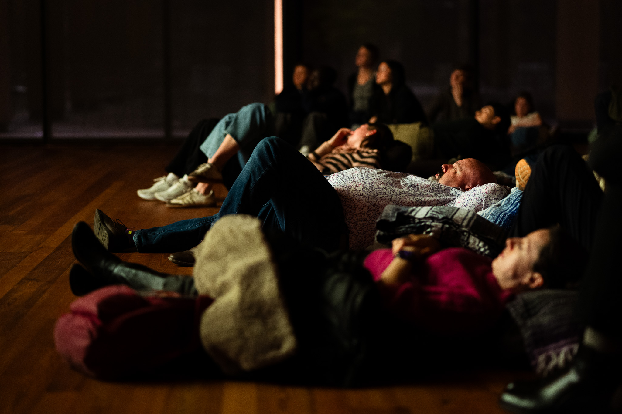 Reclining individuals watch move while laying on their backs in theater.