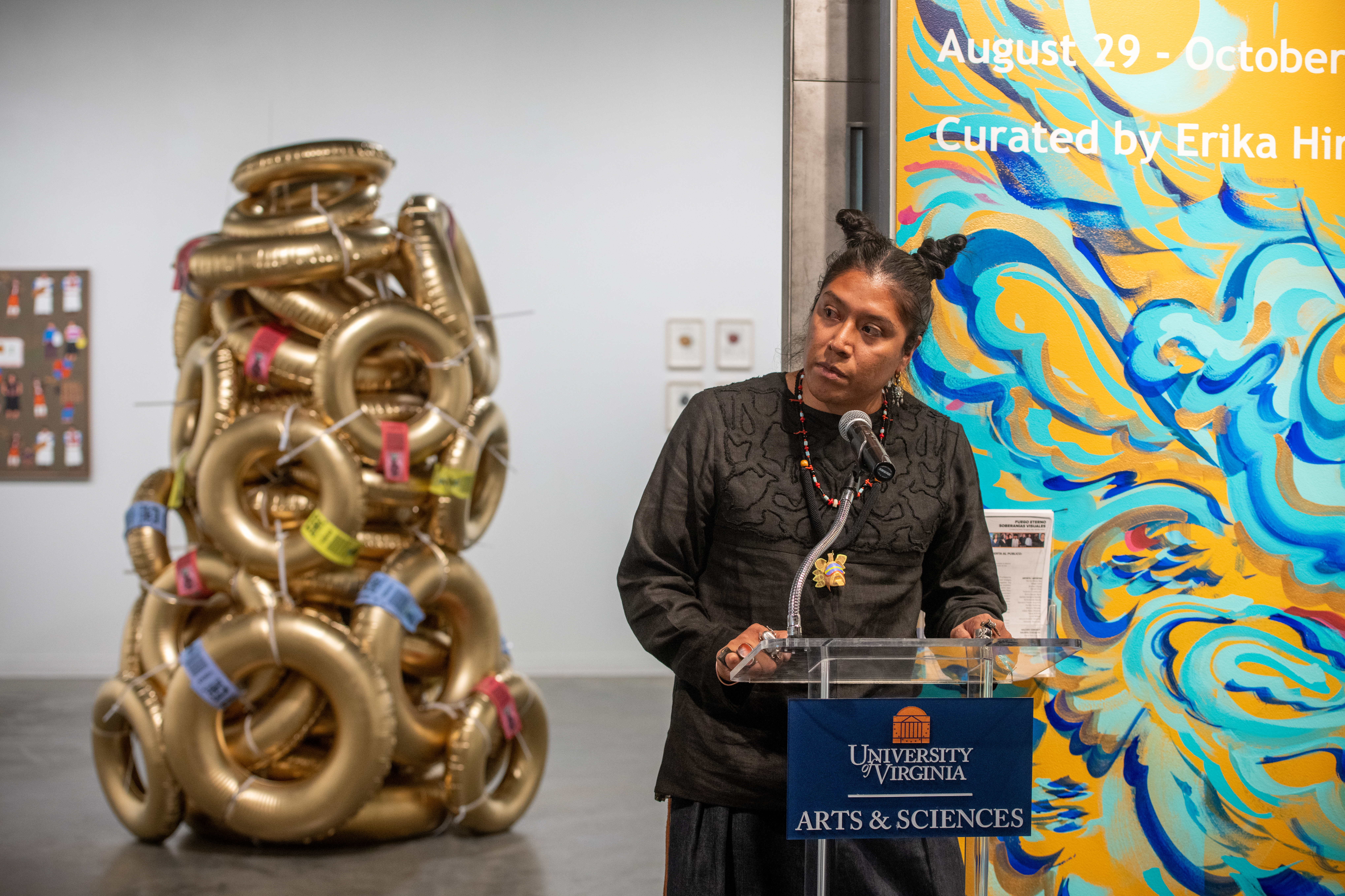 Art professor speaks from a lectern at entrance of UVA art exhibtion.