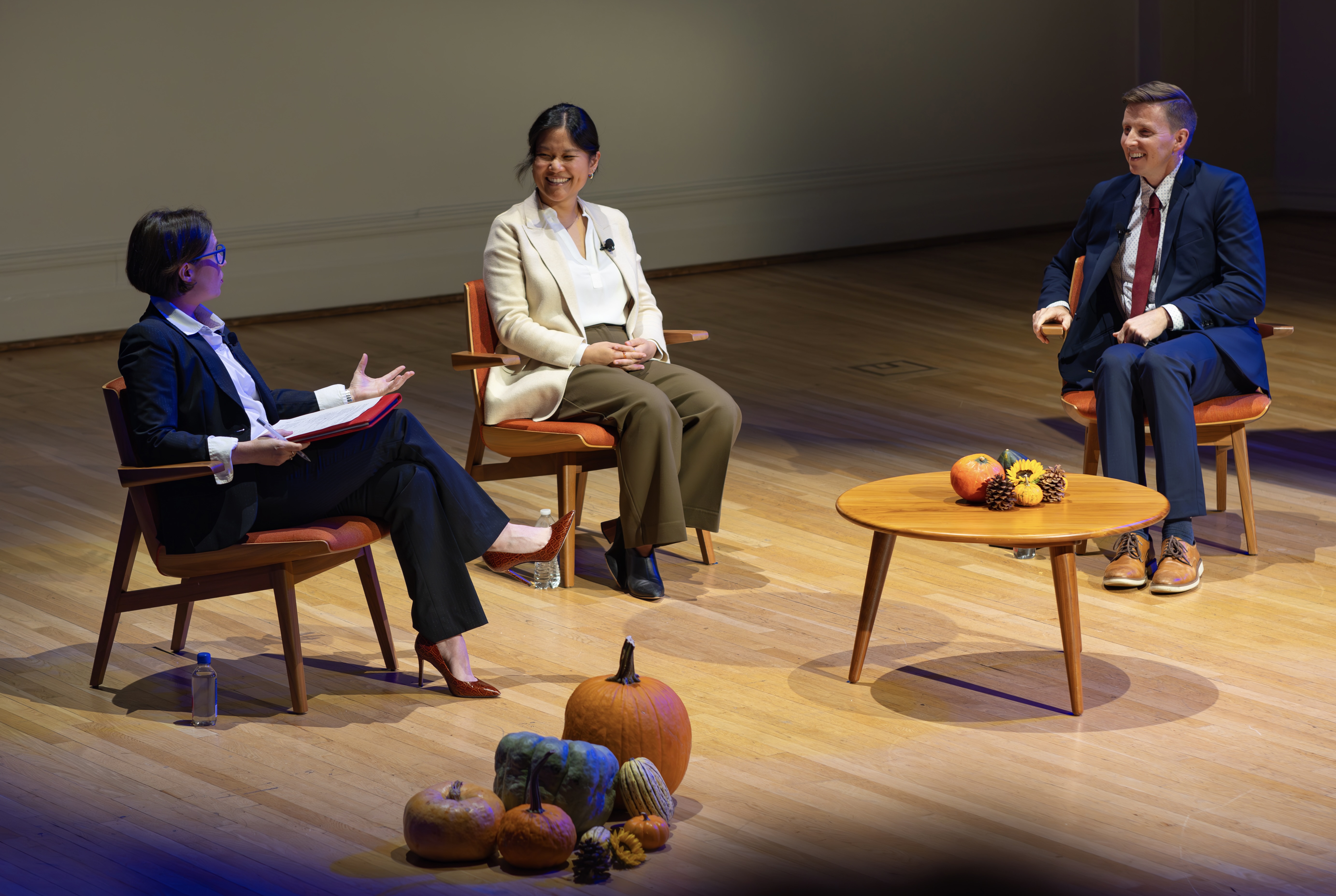 Three seated panelists laugh at a point made by the panel's moderator.
