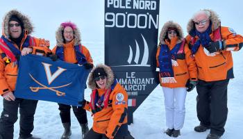 Five travelers on a UVA-sponsored cruise to the North Pole pose in the Arctic with a UVA flag.