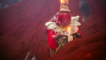 Artistic image of woman with head bowed holding a lit candle.
