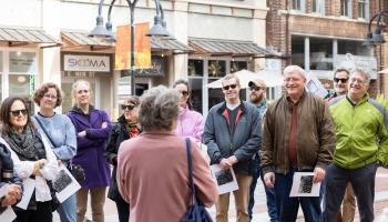 People standing and listening to a tour guide during a historical walking tour of Charlottesville.