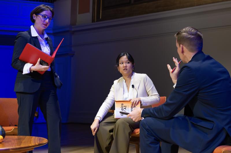 Tech journalist Karen Hao listens to a point made by a UVA faculty member while the panel moderator stands nearby listening to their conversation.