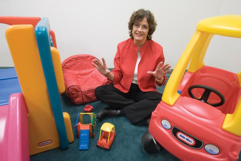 Psychology professor Judy Deloache sitting cross-legged on the floor surrounded by children's toys.